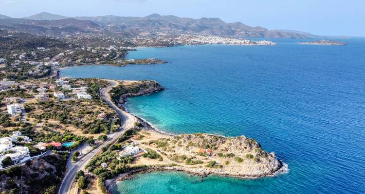 Luftaufnahme der Küstenlinie mit türkisfarbenem Wasser und üppigem Grün.