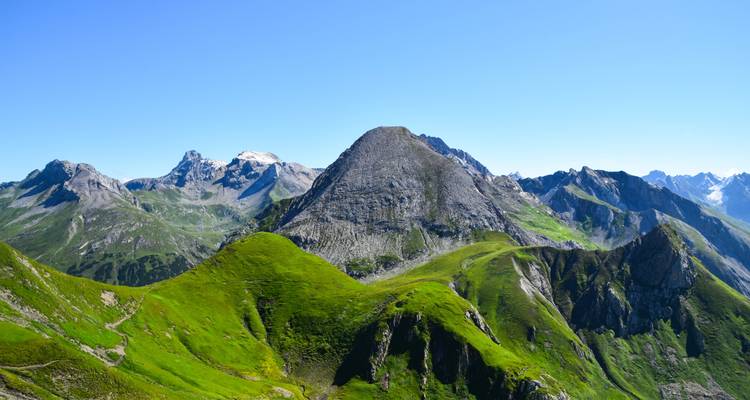 Bergkette mit grünen Hügeln und klarem blauem Himmel.