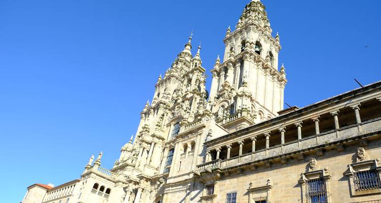 Gedetailleerd zicht op de oprijzende torens van de Kathedraal van Santiago de Compostela tegen een helderblauwe lucht