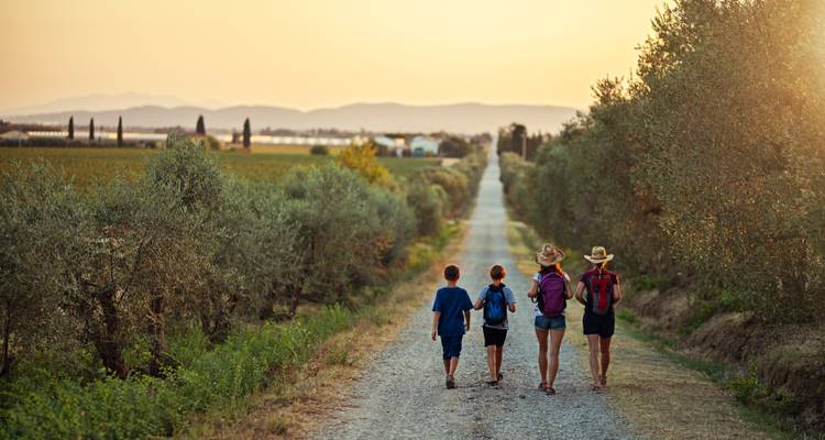 Familia caminando por un sendero a través del paisaje toscano.