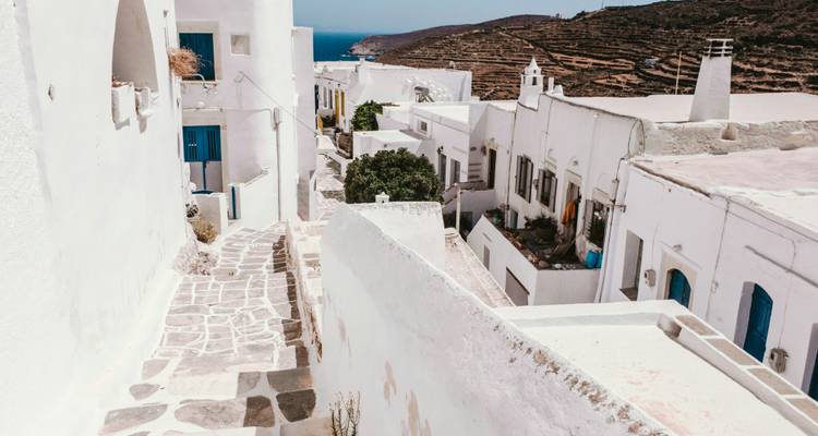 Schmale Straße mit weißen Gebäuden und blauen Türen.