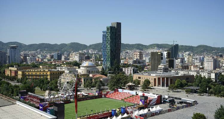 Paysage urbain avec des bâtiments modernes, un parc et des montagnes.