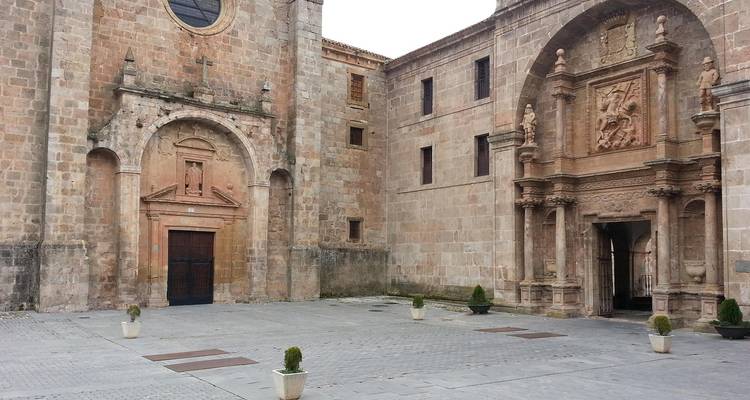 Historisch stenen gebouw in een rustige binnenplaats met bewolkte hemel.