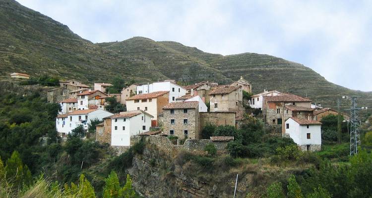 Heuveltopdorp met stenen huizen omringd door bergen.