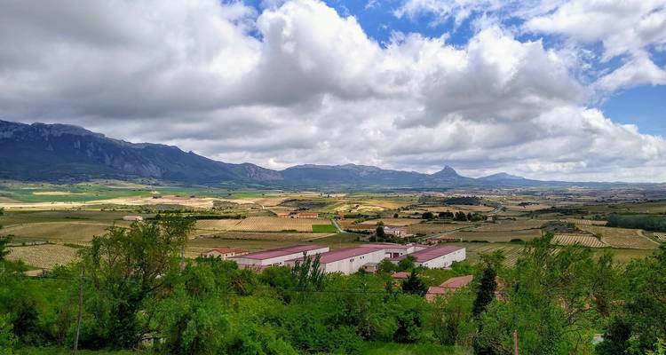 Uitgestrekt uitzicht over een vallei met bergen op de achtergrond.
