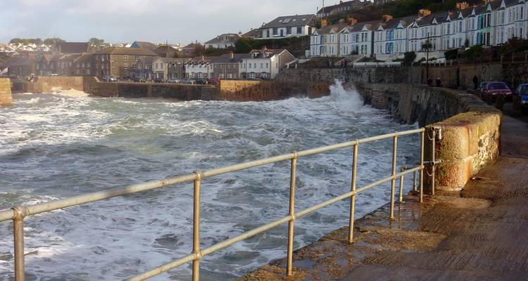 Coastal town with waves crashing against a stone wall.