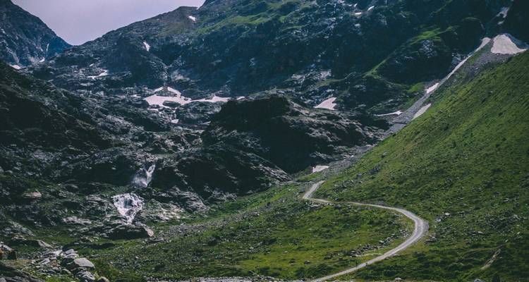 Rugged mountain terrain with a narrow road winding through it.