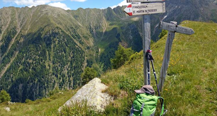 El letrero de montaña marca senderos hacia San Martín en Passeier en una cresta cubierta de hierba.