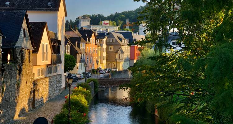 Charmantes Flussdorf mit bunten Häusern bei Sonnenuntergang.