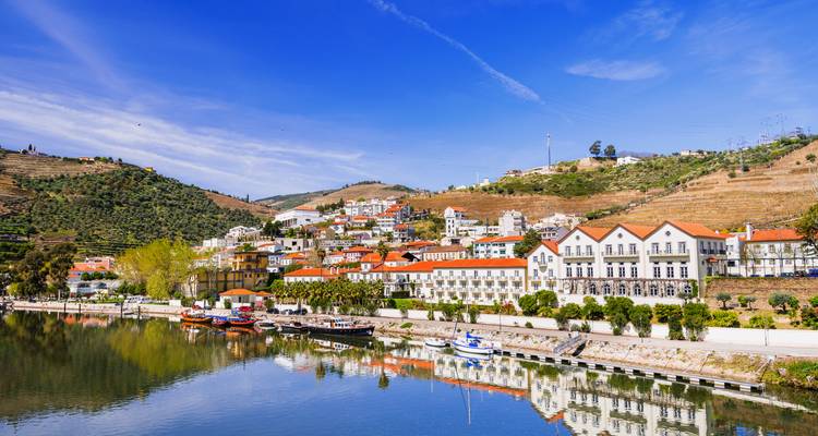 Village along a river with bright buildings and clear sky.
