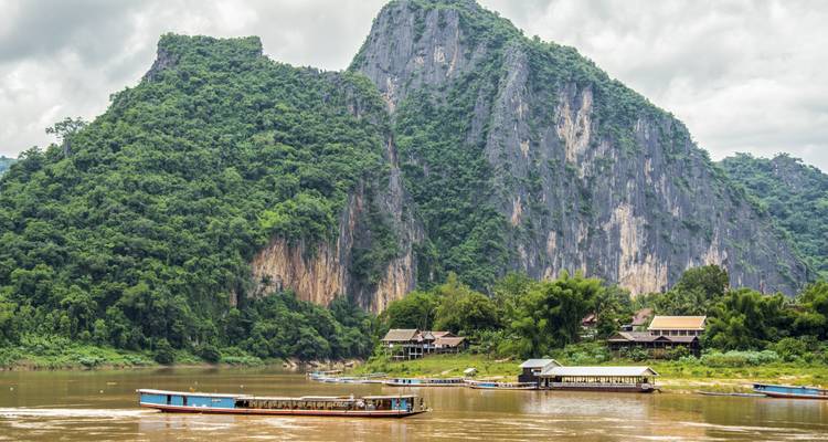 Scenic view of a river with a boat and lush green hills in the background.