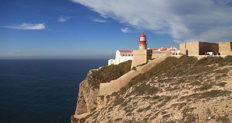 A lighthouse on the edge of a cliff overlooking the ocean.