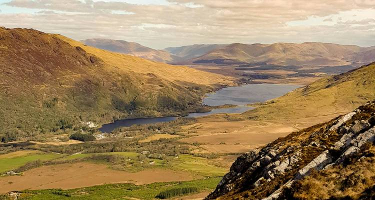 Expansive view of a valley with lakes and mountains.