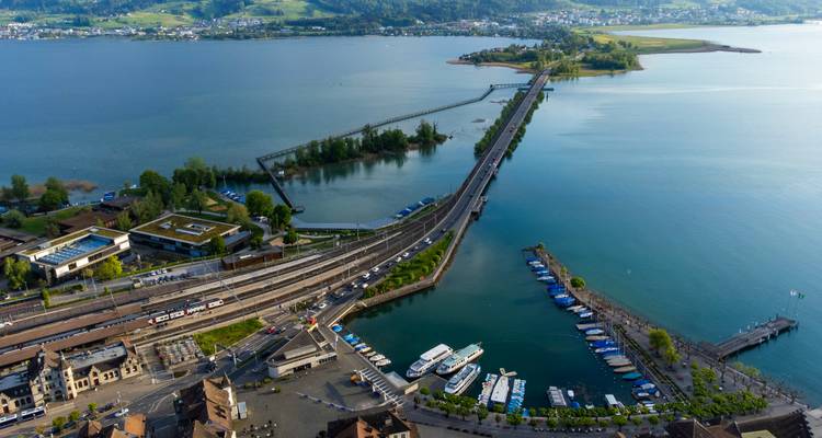 Pont traversant un vaste lac avec des bateaux amarrés le long.