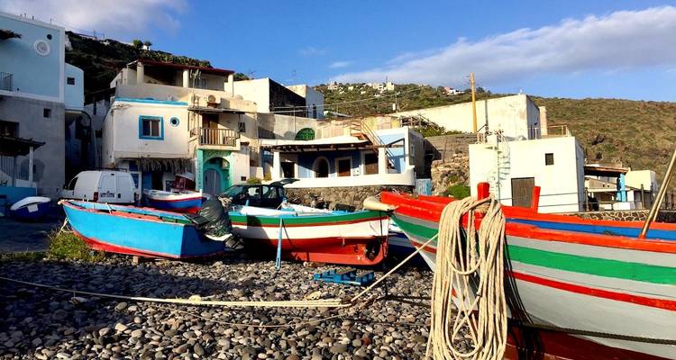 Bunte Boote an einem felsigen Ufer mit malerischen Küstenhäusern.