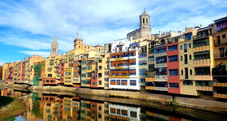 Bunte Gebäude entlang eines Flussufers in einer historischen Innenstadt.