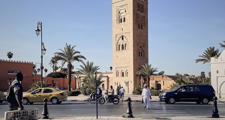Scène de rue près de la Mosquée Koutoubia avec des habitants et du trafic à Marrakech.