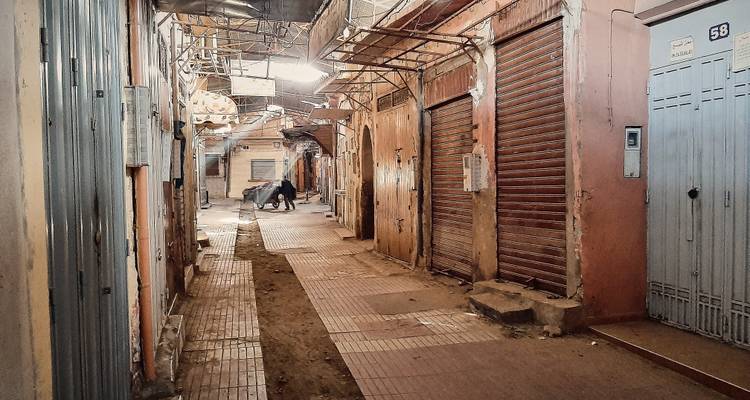 Ruelle étroite et vide de la médina de Marrakech avec des volets fermés et une charrette à mulet devant.