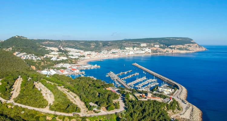 Küstenstadt mit Yachthafen und hügeligem Hintergrund.