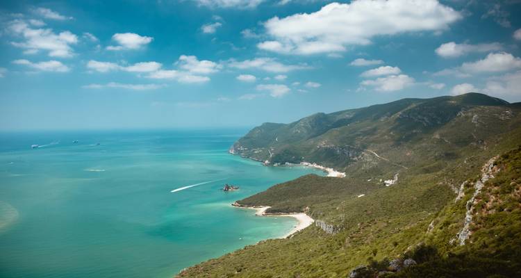 Küstenlandschaft mit grünen Hügeln und klarem Meer.