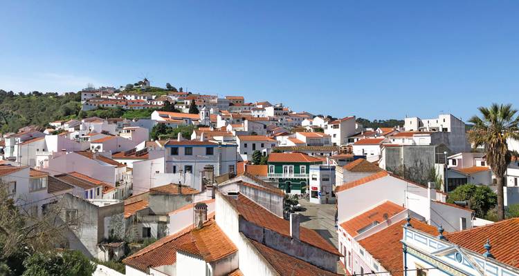 Panoramablick auf eine weiß getünchte Hangstadt mit roten Ziegeldächern unter einem klaren blauen Himmel.