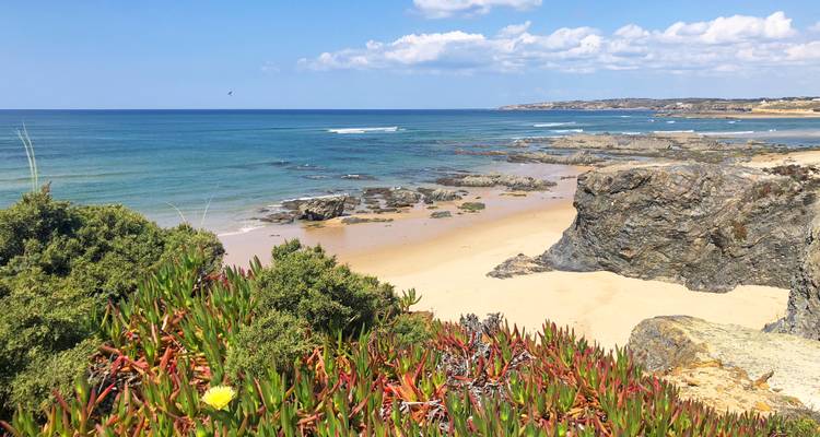 Zerklüftete Küstenlinie mit Sandstrand, Felsformationen und klarem blauem Atlantikwasser an einem sonnigen Tag.