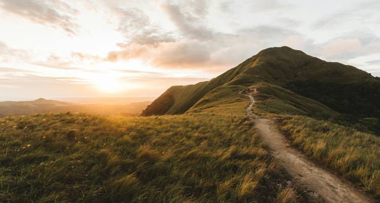Sentier de randonnée pittoresque le long d'une crête avec vue sur les montagnes au coucher du soleil.