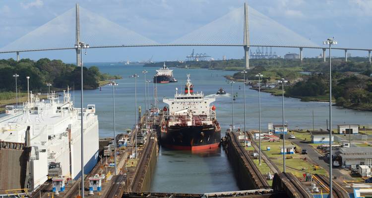 Des navires traversant le canal de Panama avec un pont en arrière-plan.