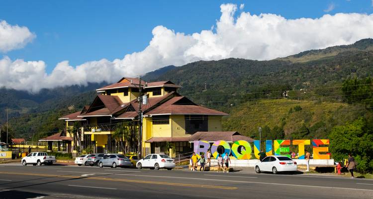Panneau de Boquete avec des gens debout devant, montagnes en arrière-plan.