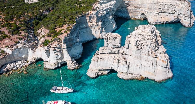 Falaises côtières avec voiliers dans une eau turquoise.
