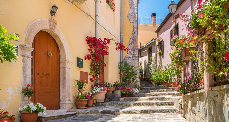 A charming cobblestone street lined with colorful flowers and old buildings.