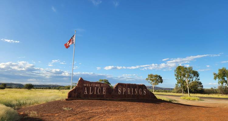 Panneau de bienvenue d'Alice Springs avec un drapeau en arrière-plan.