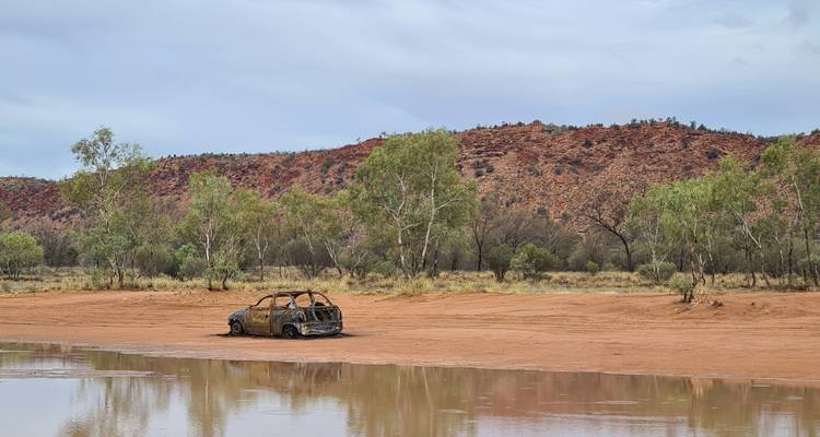 Voiture abandonnée dans un lit de rivière asséché.