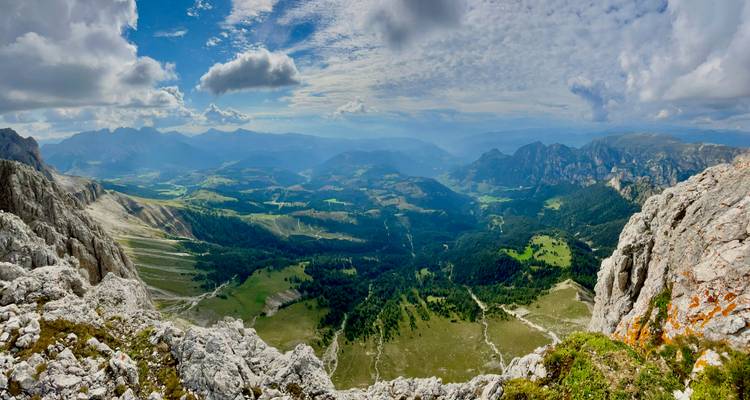 Panoramic view of valleys and distant mountains under a cloudy sky.