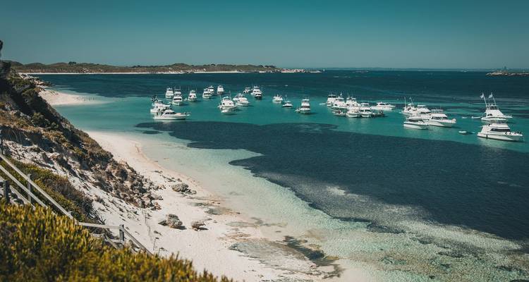 Aerial view of a beach with moored boats on turquoise water.