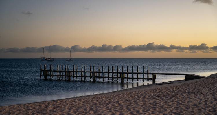 Sunset view over a beach with a pier.