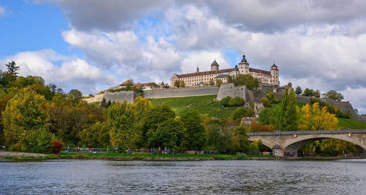 Château sur une colline avec une rivière et un pont.