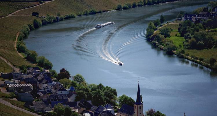 Vue sur la rivière avec des bateaux et un village.