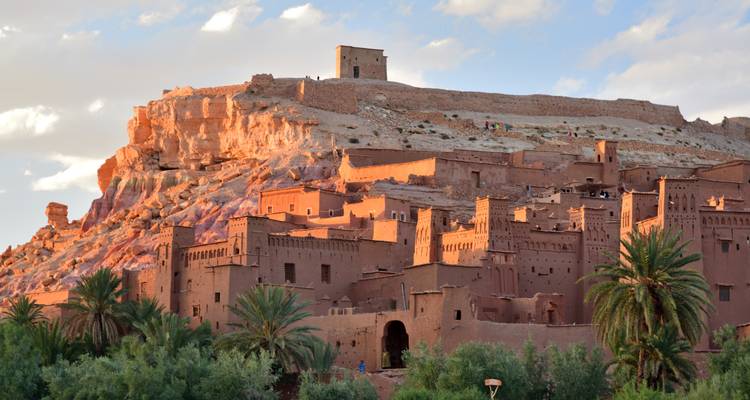 Kasbah marroquí ancestral al pie de una montaña, bañada por la luz del atardecer.