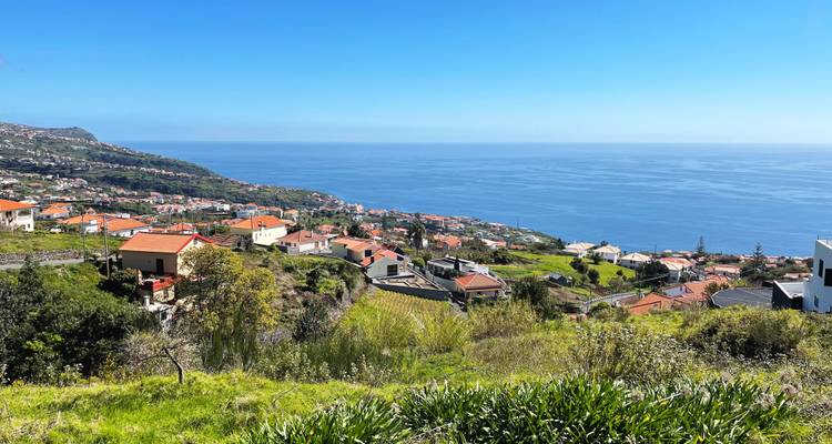 Village à flanc de colline avec des maisons aux toits rouges surplombant le vaste océan Atlantique par une journée claire et lumineuse.