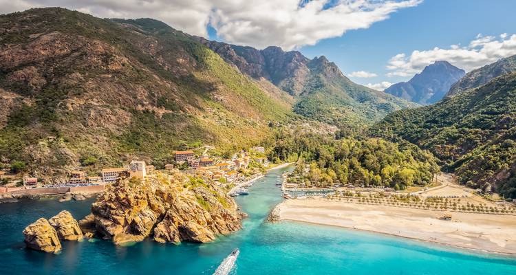 Ville côtière avec une eau bleue claire et une végétation luxuriante.