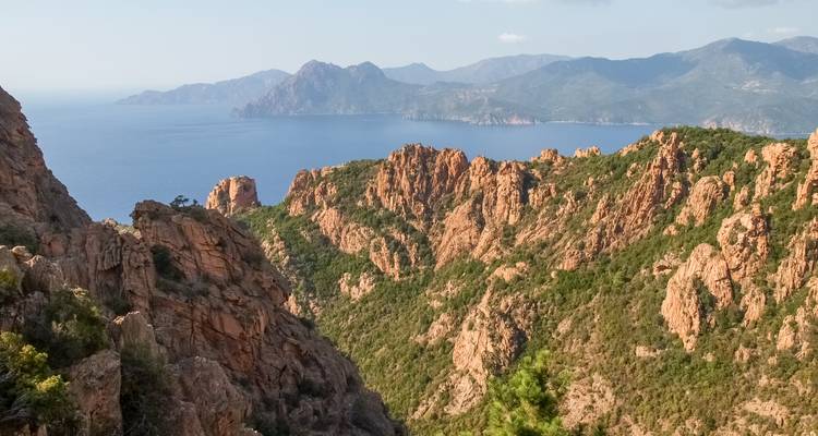 Terrain rocheux avec vue sur mer en arrière-plan.