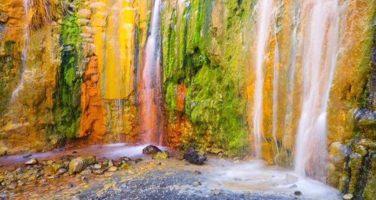 Cascade minérale aux couleurs vives avec un environnement luxuriant.