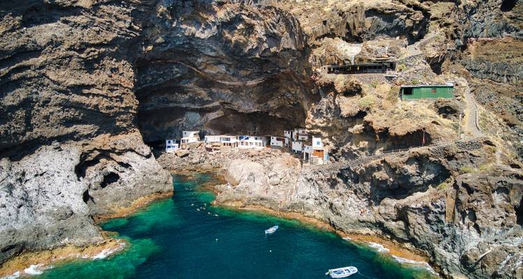 Cueva costera con pequeños botes amarrados.