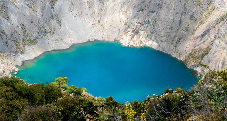 Un lac de cratère volcanique bleu profond entouré d'un terrain rocheux.