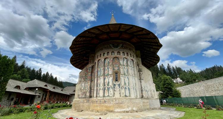 Murs ornés de fresques d'un monastère historique avec des personnes à proximité.