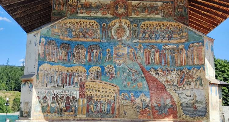 Mur peint à fresque coloré représentant des scènes religieuses.