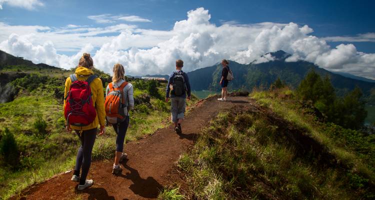 Group of hikers walking along a mountain path with a scenic view.