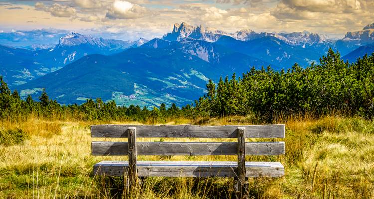 Wooden bench overlooking a vast mountain range.