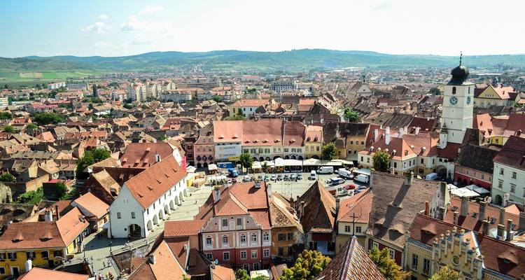 Vue panoramique de Sibiu avec des bâtiments historiques et des collines vallonnées.